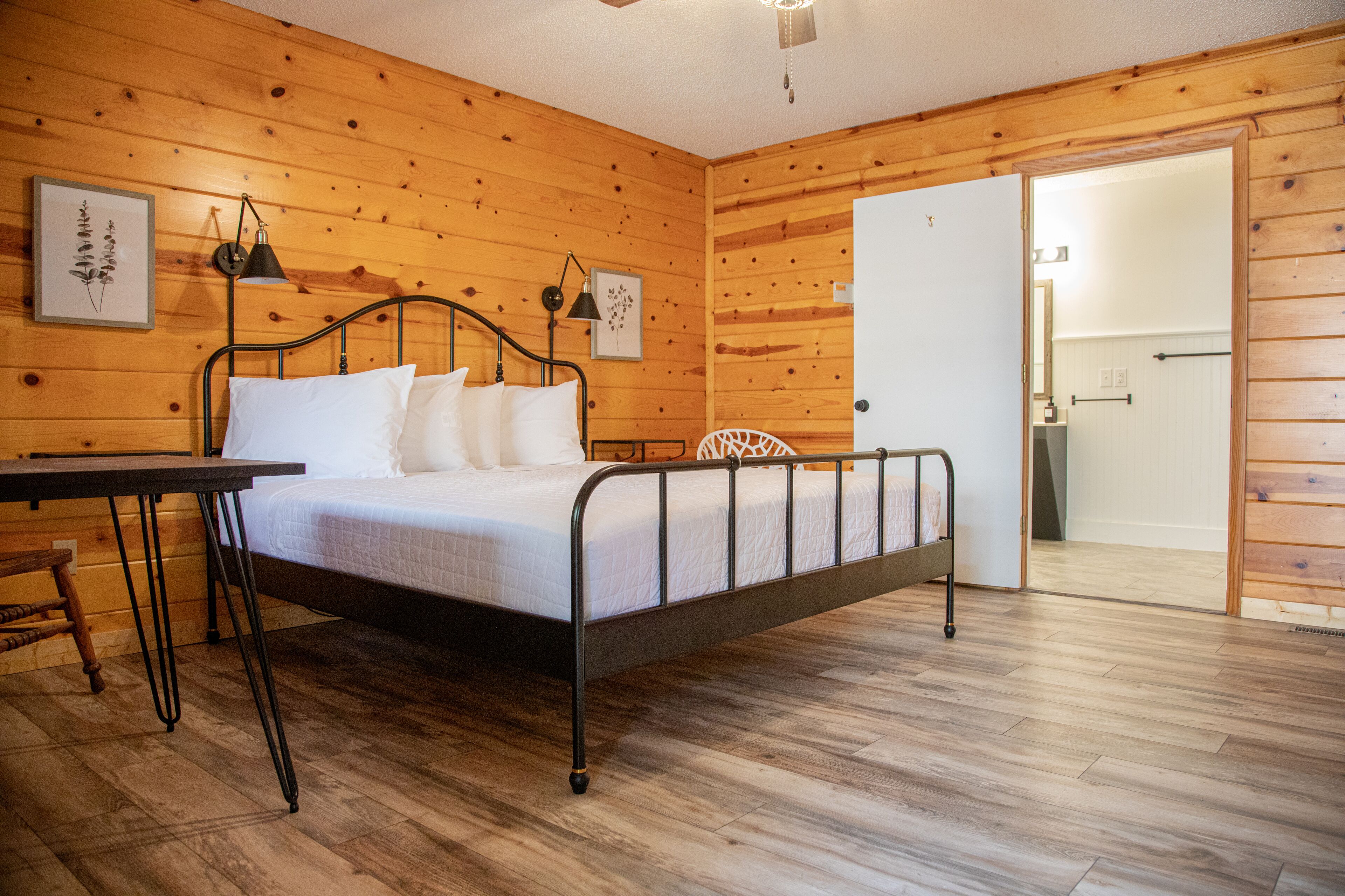 A wooden-paneled room with a bed, a desk, and a chair.