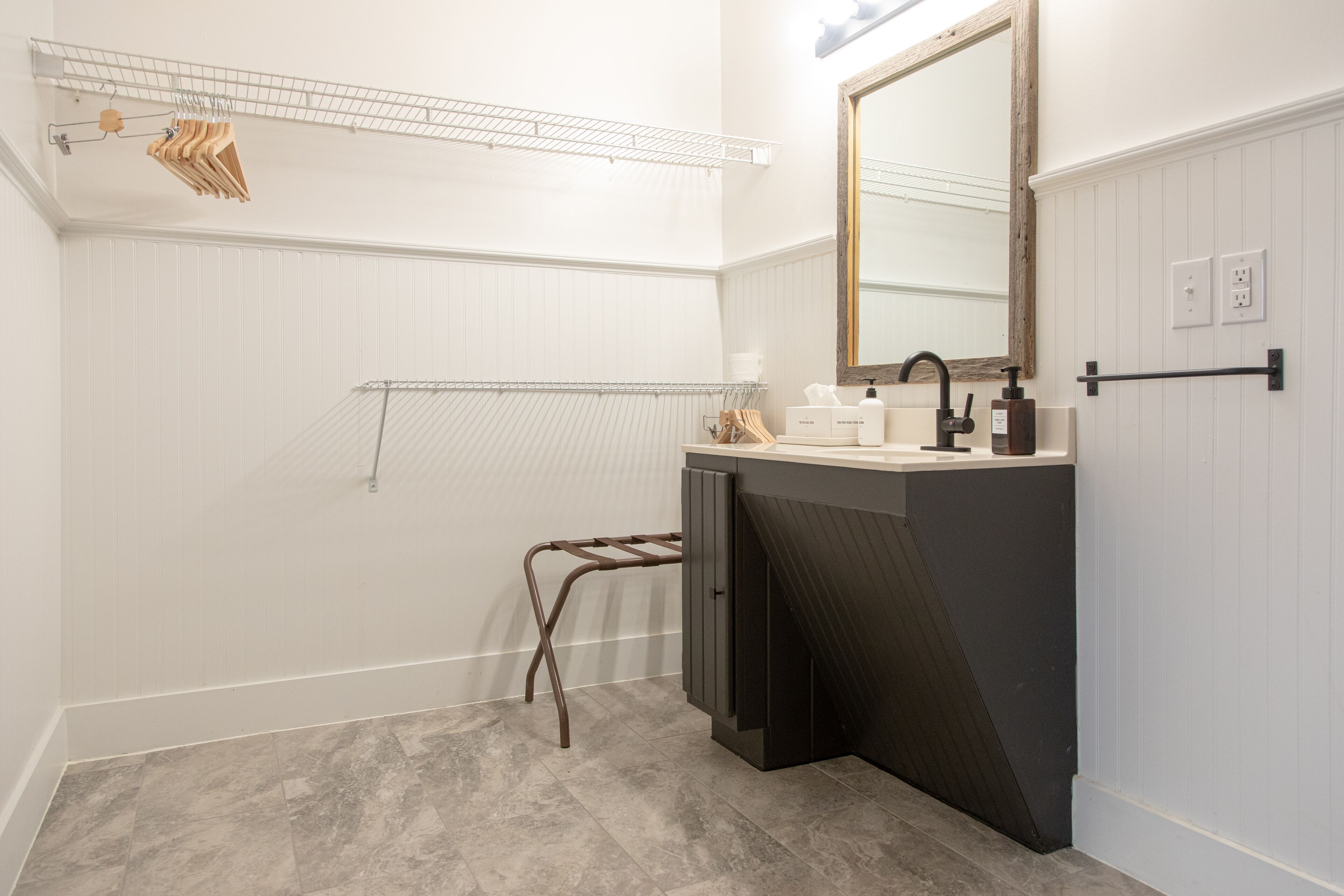 A bathroom with a dark vanity, a mirror, a towel rack, and a shower area.