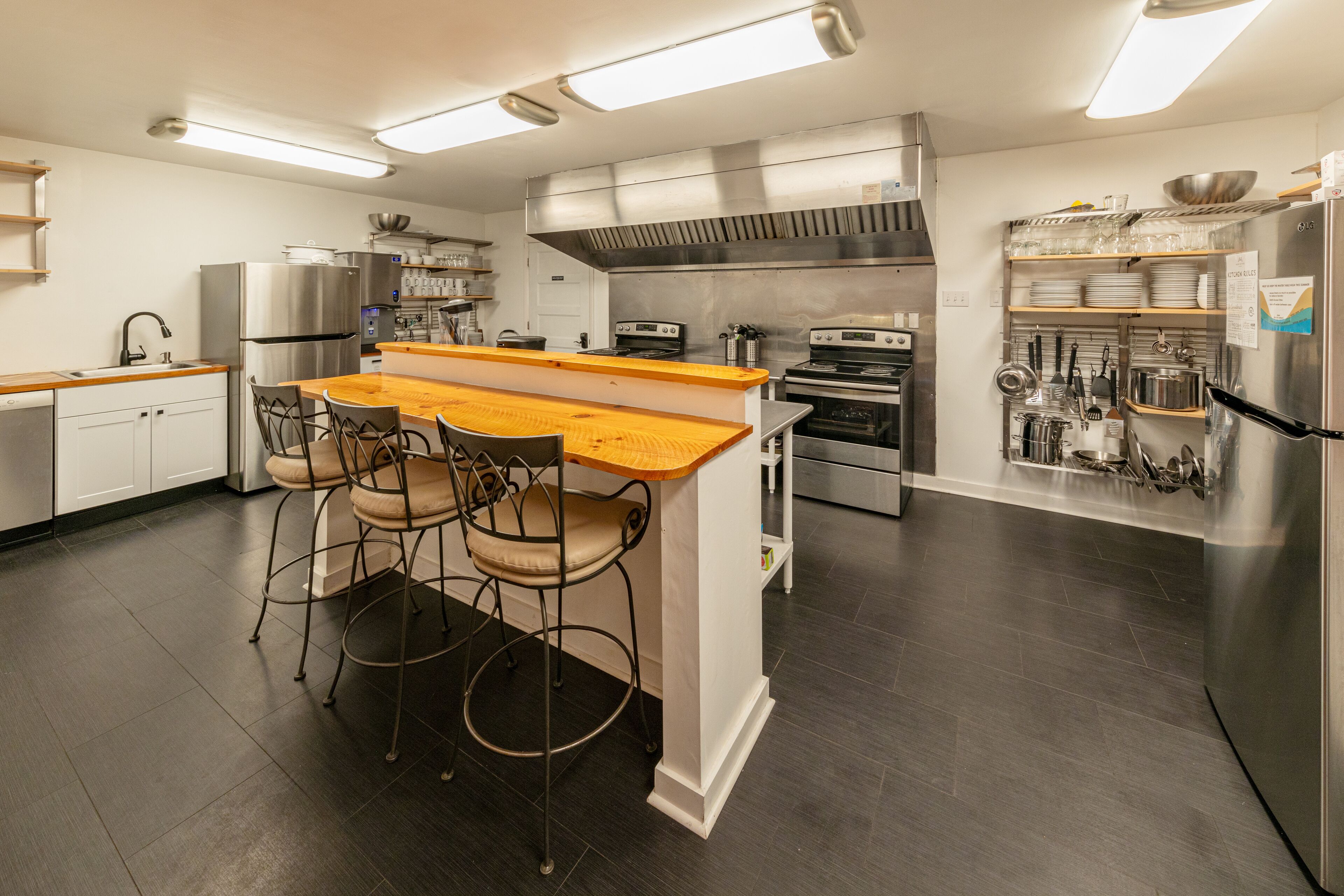 A modern kitchen with a central island, bar stools, stainless steel appliances, and ample counter space.