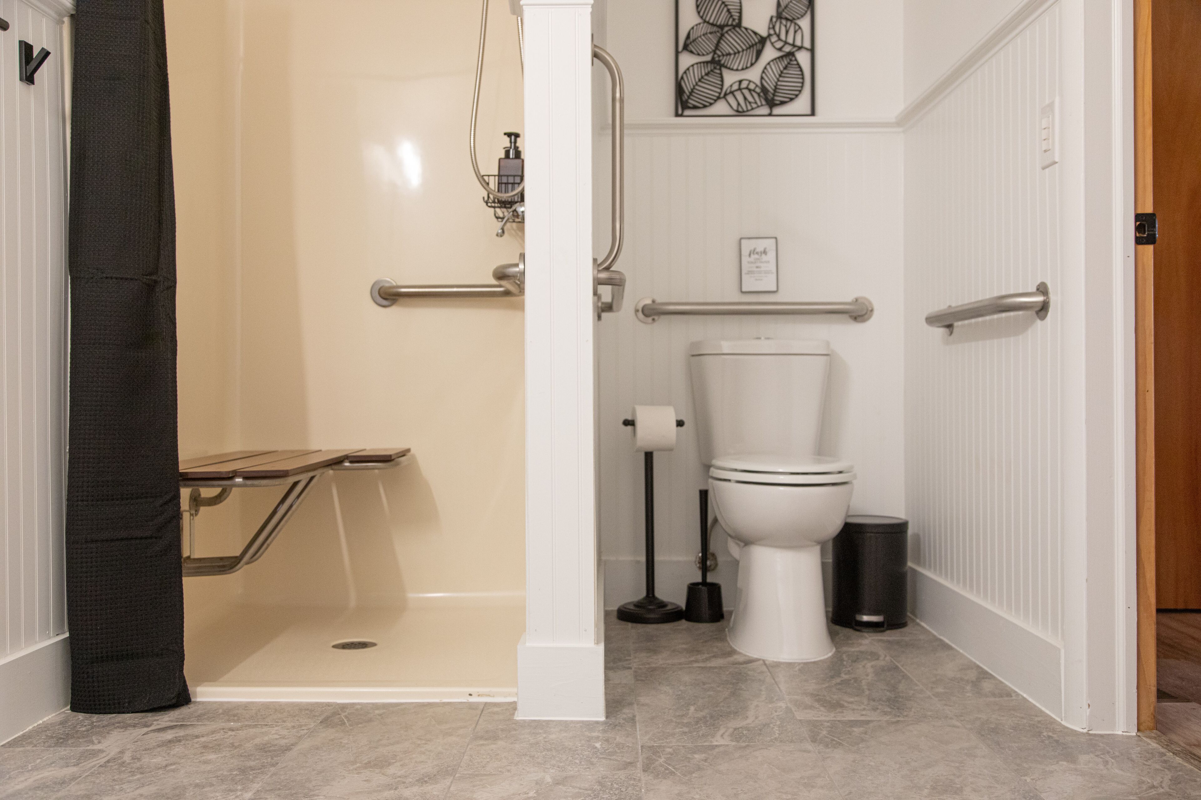 A bathroom with a shower, toilet, and grab bars.