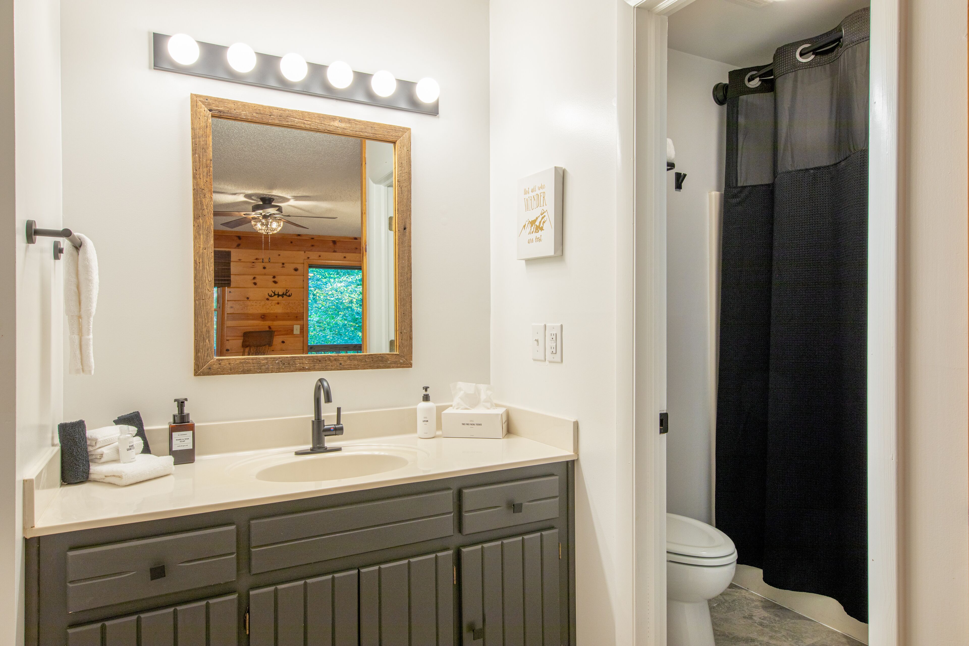Une salle de bain équipée d’un meuble-lavabo, d’un lavabo, d’un miroir et d’un rideau de douche.