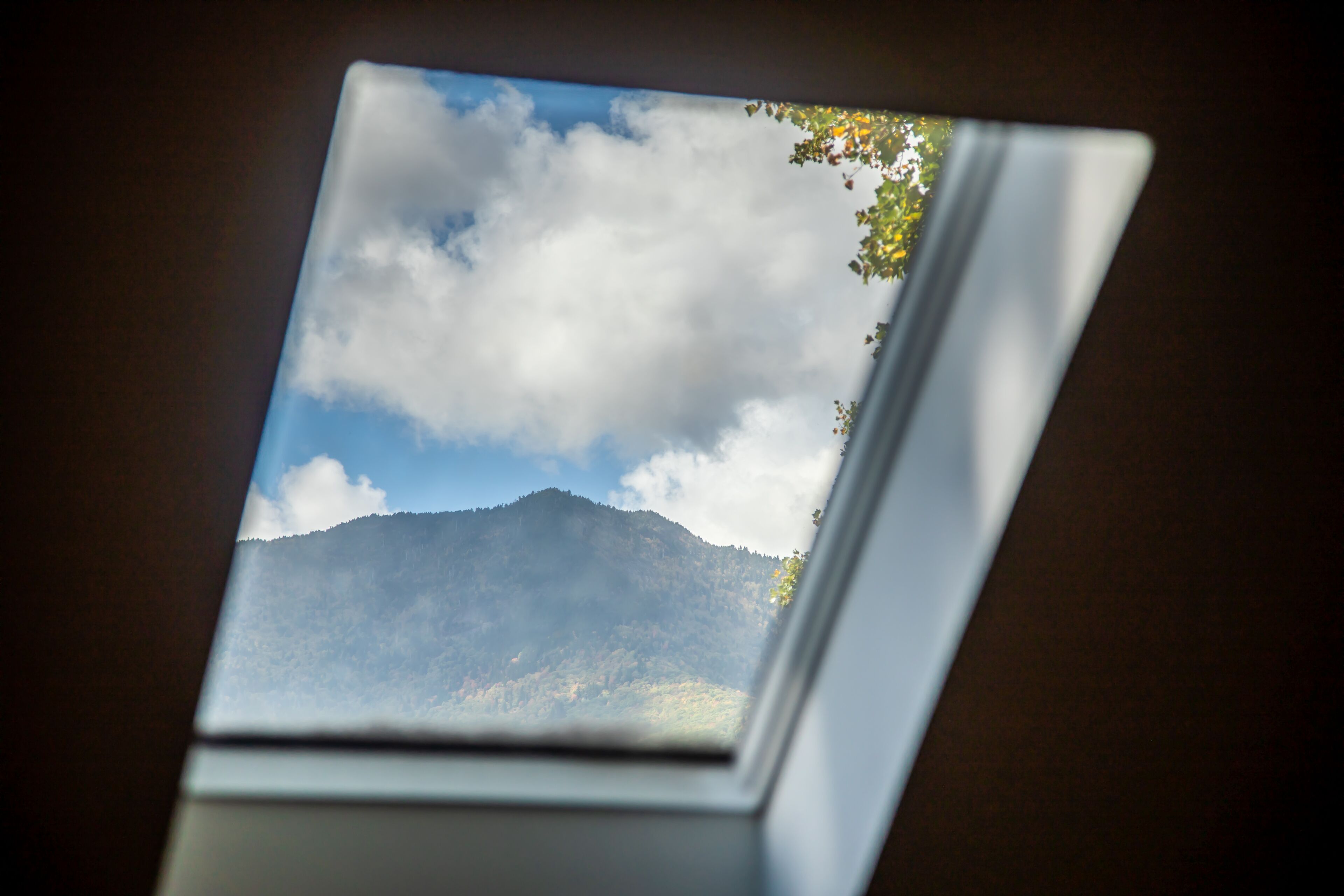 Ein Fenster mit Blick auf Berg und Himmel.