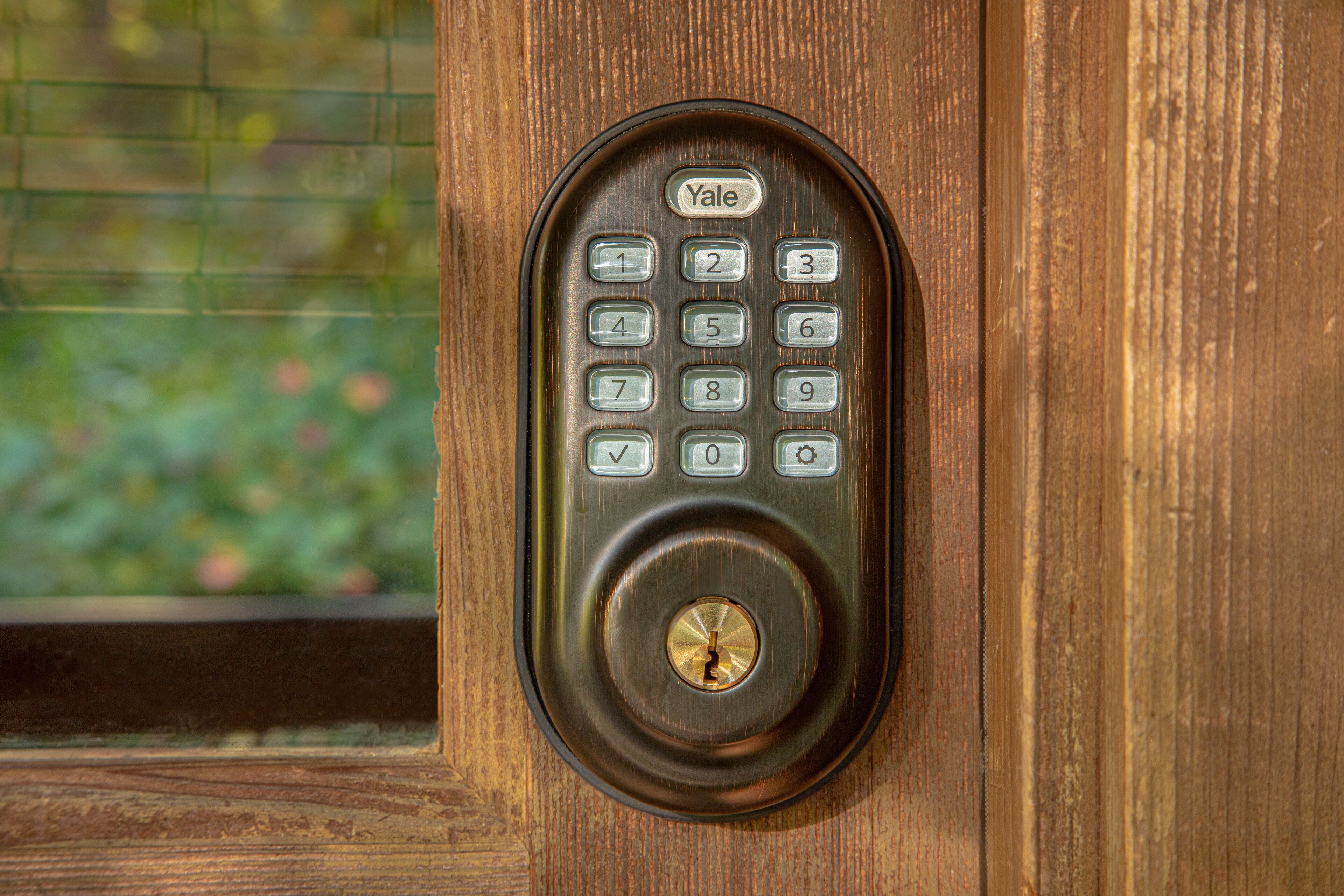 A Yale keypad lock on a wooden door.