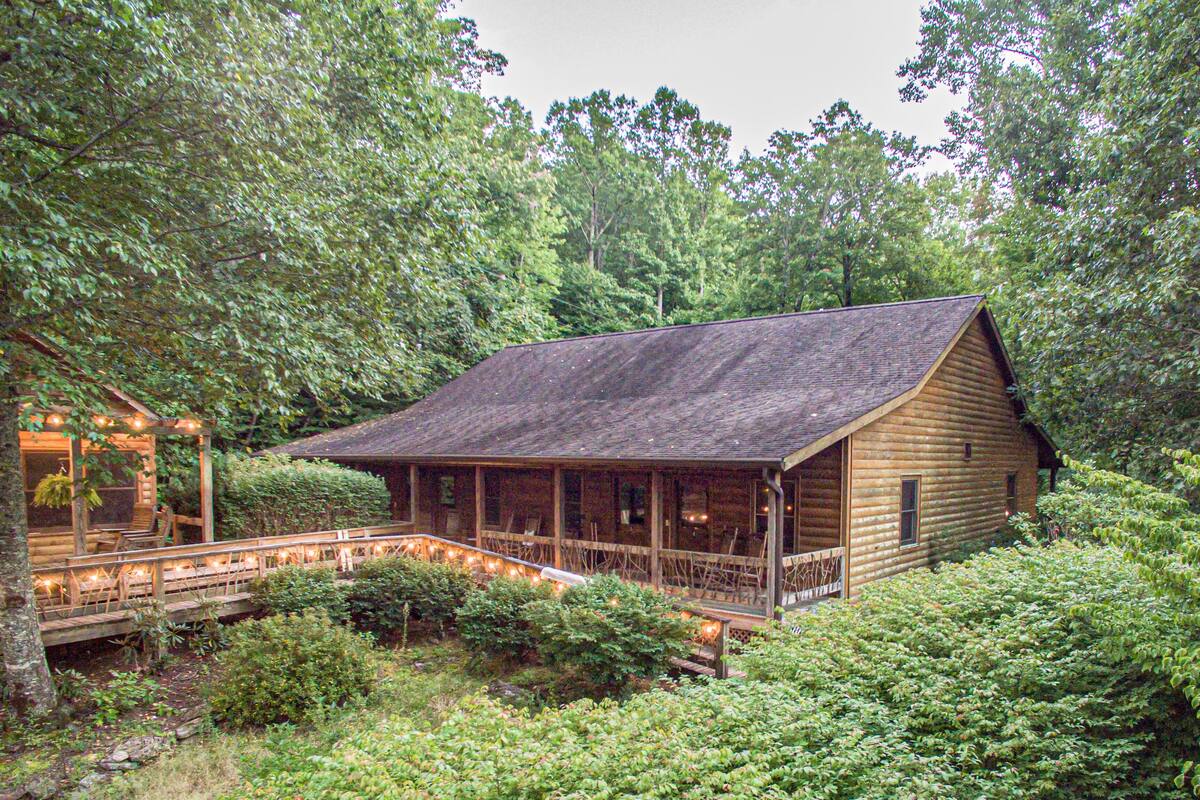 Ein rustikales Blockhaus mit Veranda, umgeben von dichtem Wald.