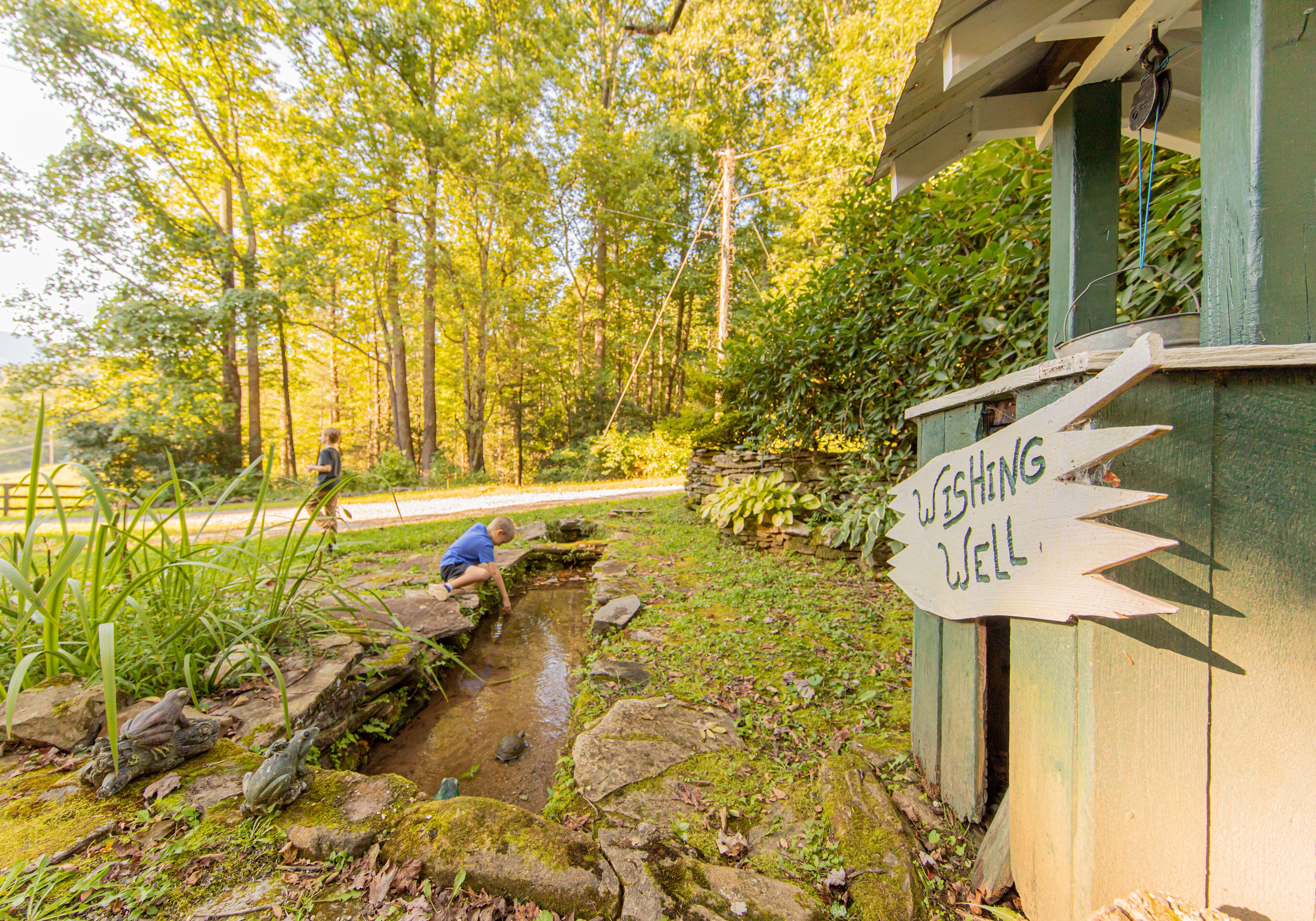 Une construction rustique en bois, sur laquelle est accrochée une pancarte indiquant : « Puits aux vœux ».