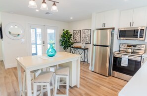 Una cocina moderna con armarios blancos, electrodomésticos de acero inoxidable y piso de madera.