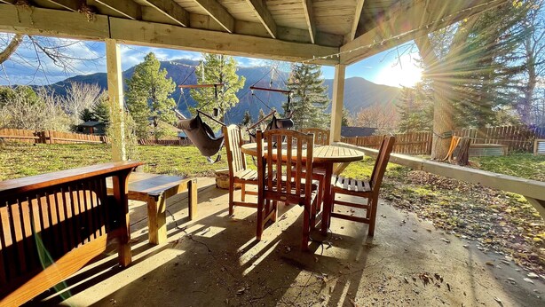 Une terrasse extérieure avec des meubles en bois, une balançoire et une vue sur les montagnes.
