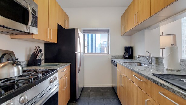 Una cocina con armarios de madera, estufa de acero inoxidable, microondas y refrigerador.