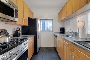 A kitchen with wooden cabinets, a stainless steel stove, a microwave, and a refrigerator.