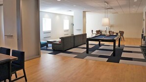 Una habitación con mesa de billar, sofá y comedor con sillas.