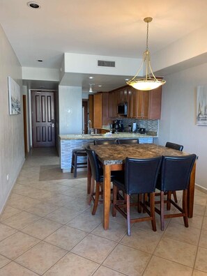 A modern kitchen with wooden cabinets, a central island, and a dining area with a large table and chairs.