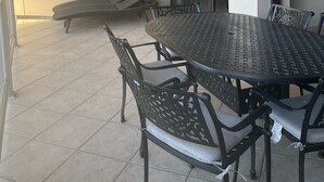 Terrassa exterior coberta amb taula rodona i cadires, ventilador de sostre i porta corredissa de vidre.