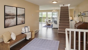 A spacious living area with a wooden bench, a patterned rug, and a staircase leading to an upper level. - Mint Private Lakefront Skaneateles, 4BR/2 Bath w/50ft Lake Frontage w/Dock (Skaneateles)
