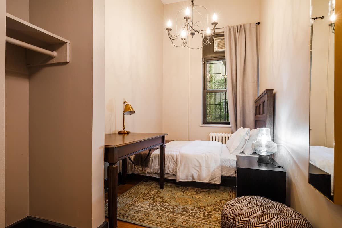 A bedroom with a bed, bedside table, lamp, and a window with curtains.