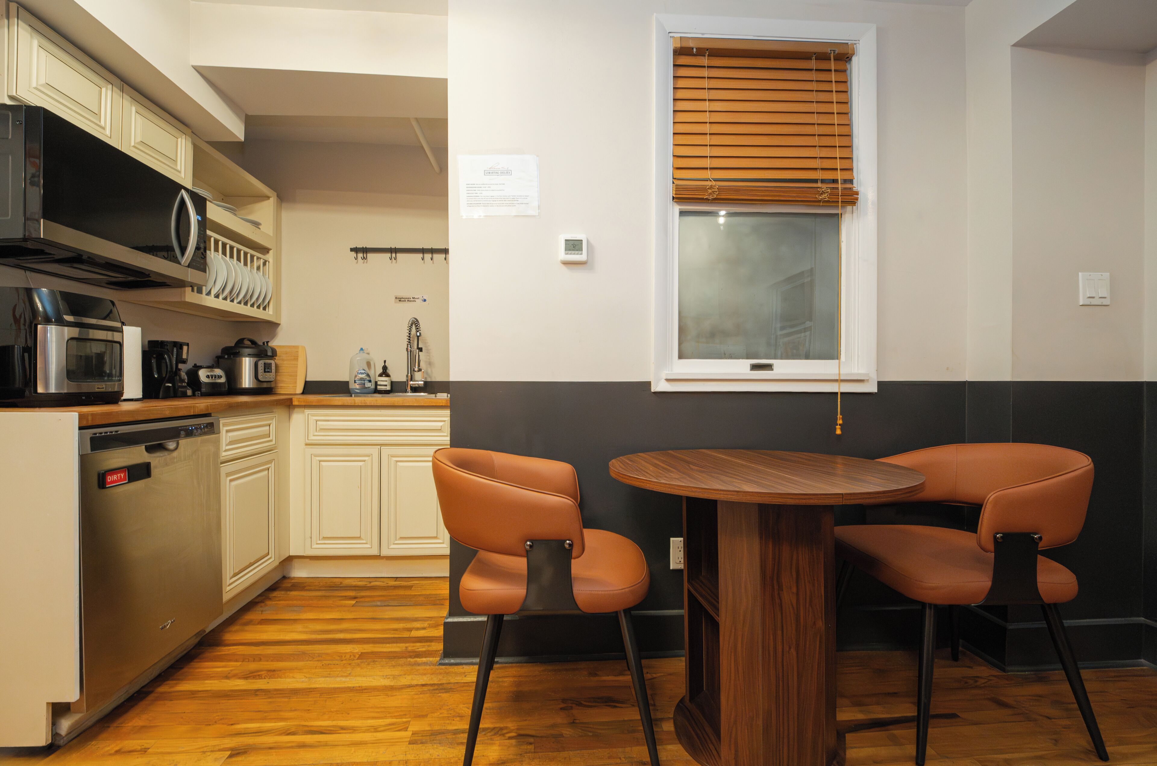 A compact kitchen with a dining area, equipped with a microwave, coffee maker, and a dishwasher.