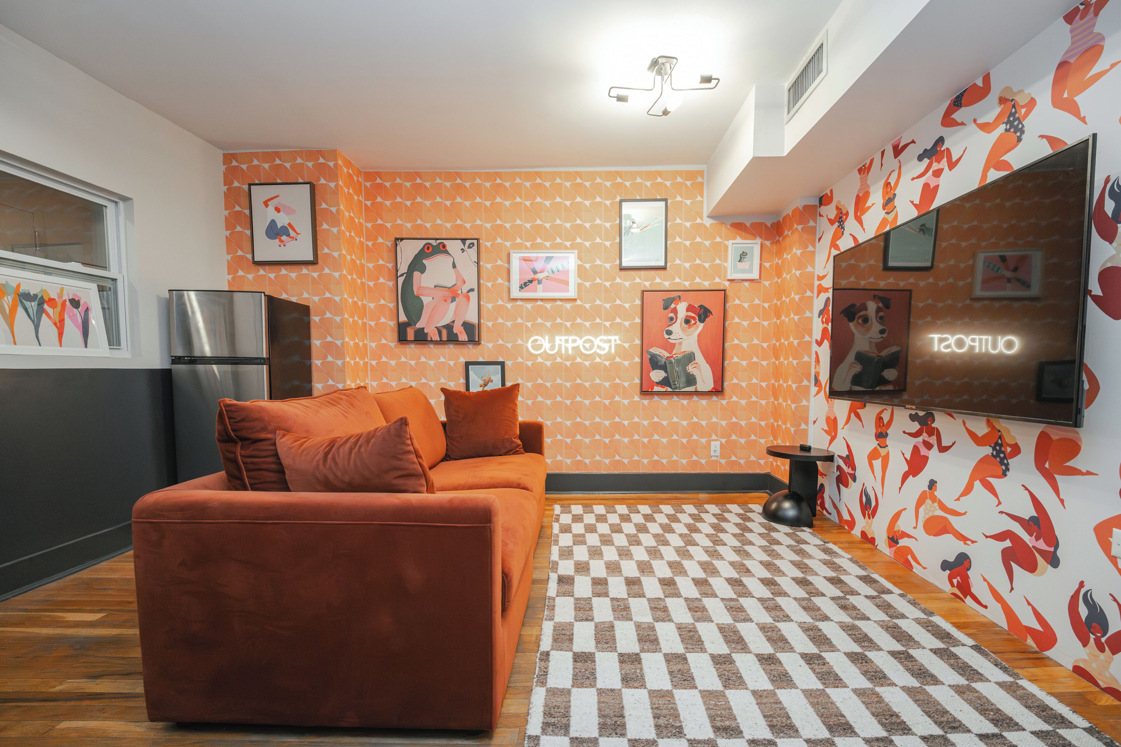 A room with a checkered floor, a sofa, and a wall with framed artwork.