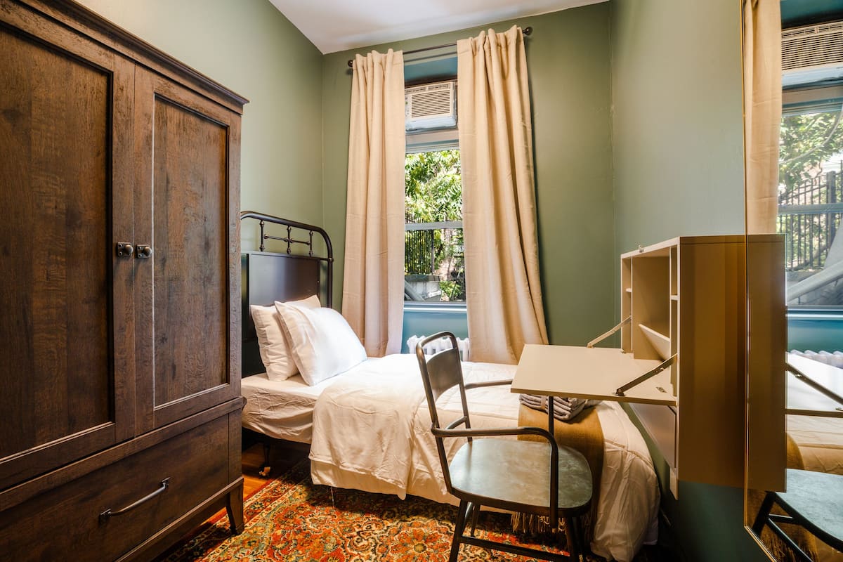 A room with a bed, a desk, a chair, and a wardrobe.
