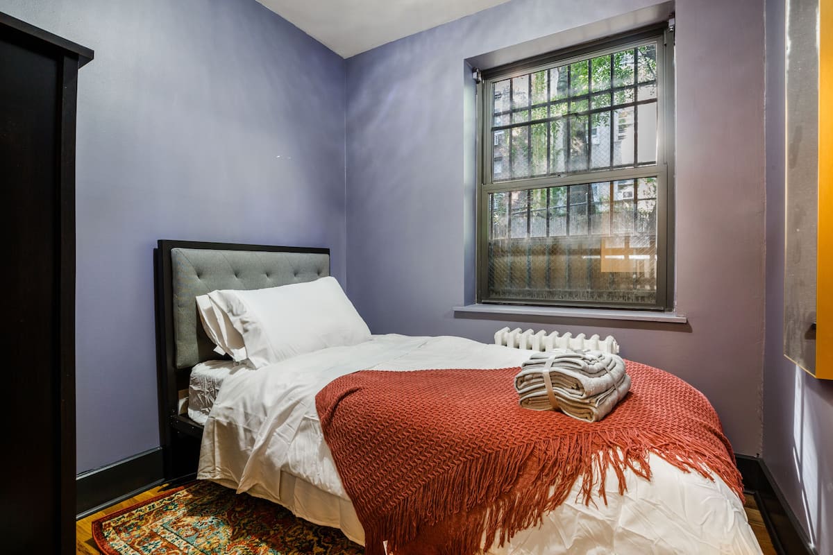 A bedroom with a bed, a window, and a radiator.