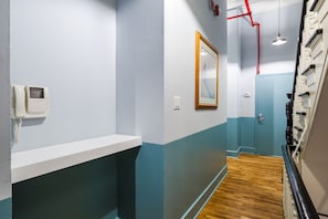 Un pasillo con un teléfono blanco, un cuadro en la pared y suelo de madera.