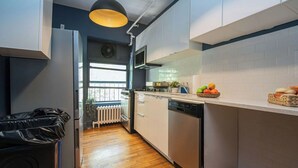 Uma cozinha moderna com armários brancos, máquina de lavar louça e janela com vista.