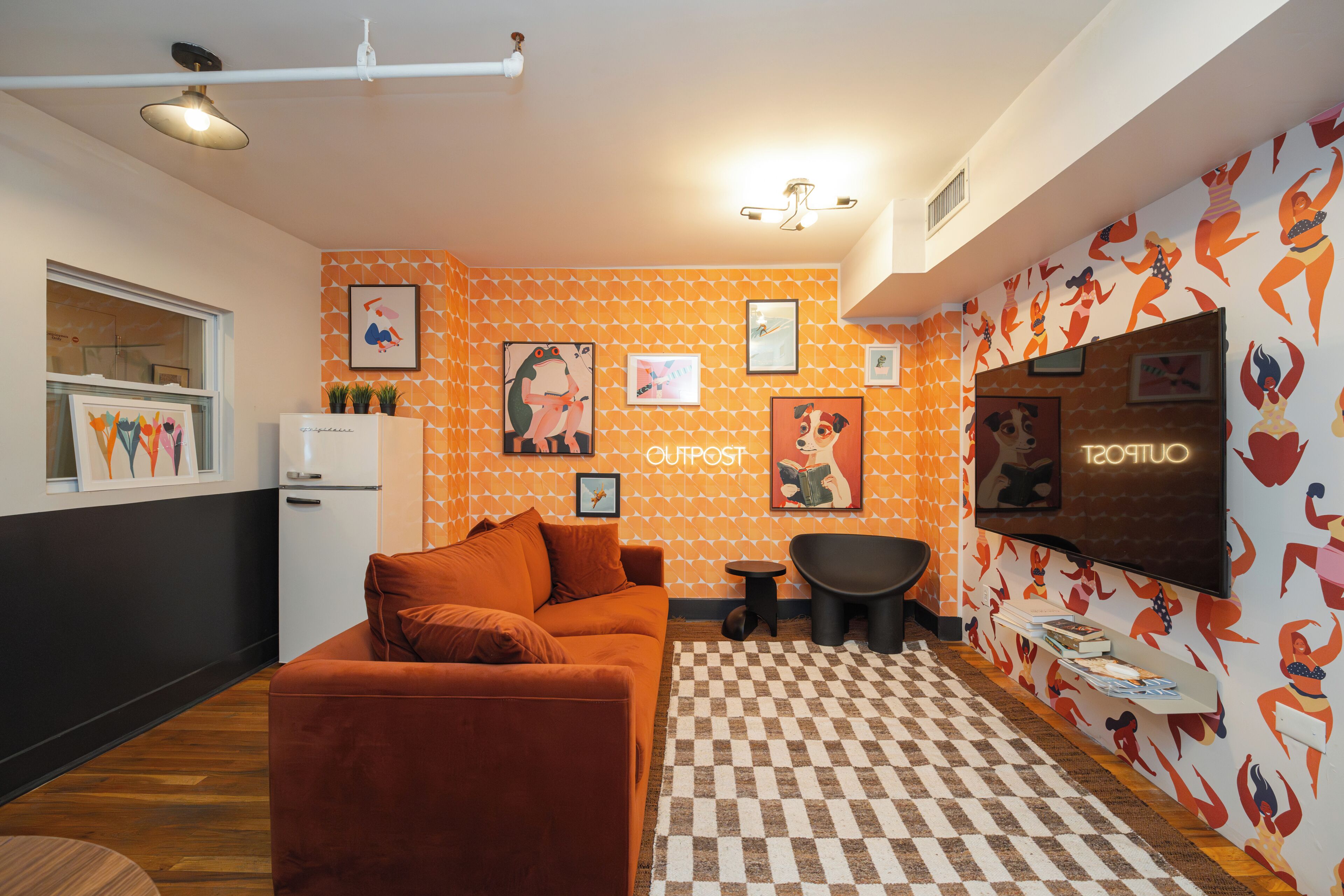 Un espacio habitable compacto con kitchenette, un sofá, una mesita y un televisor montado en la pared.