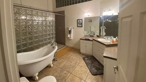 Ein Badezimmer mit freistehender Badewanne, einem Waschtisch mit Spiegel und einer Duschkabine.
