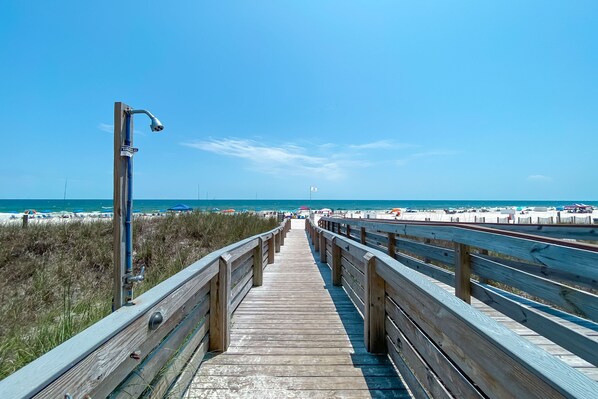 A wooden boardwalk leading to a beach with a clear sky.