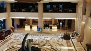 Eine Hotellobby mit einer zentralen Rezeption, Sitzbereichen und einer dekorativen Springbrunnen.