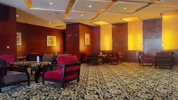 Un hall d’hôtel avec des espaces aménagés pour s’asseoir, des tables et une moquette à motifs.