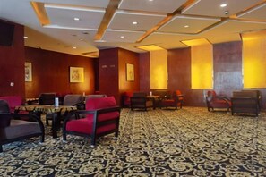 Un hall d’hôtel avec des espaces aménagés pour s’asseoir, des tables et une moquette à motifs.