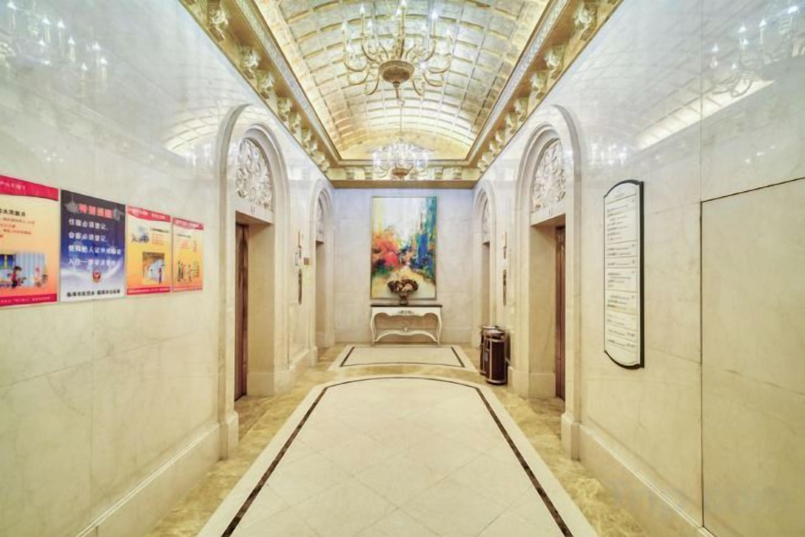A corridor with a marble floor, a chandelier, and a painting on the wall.