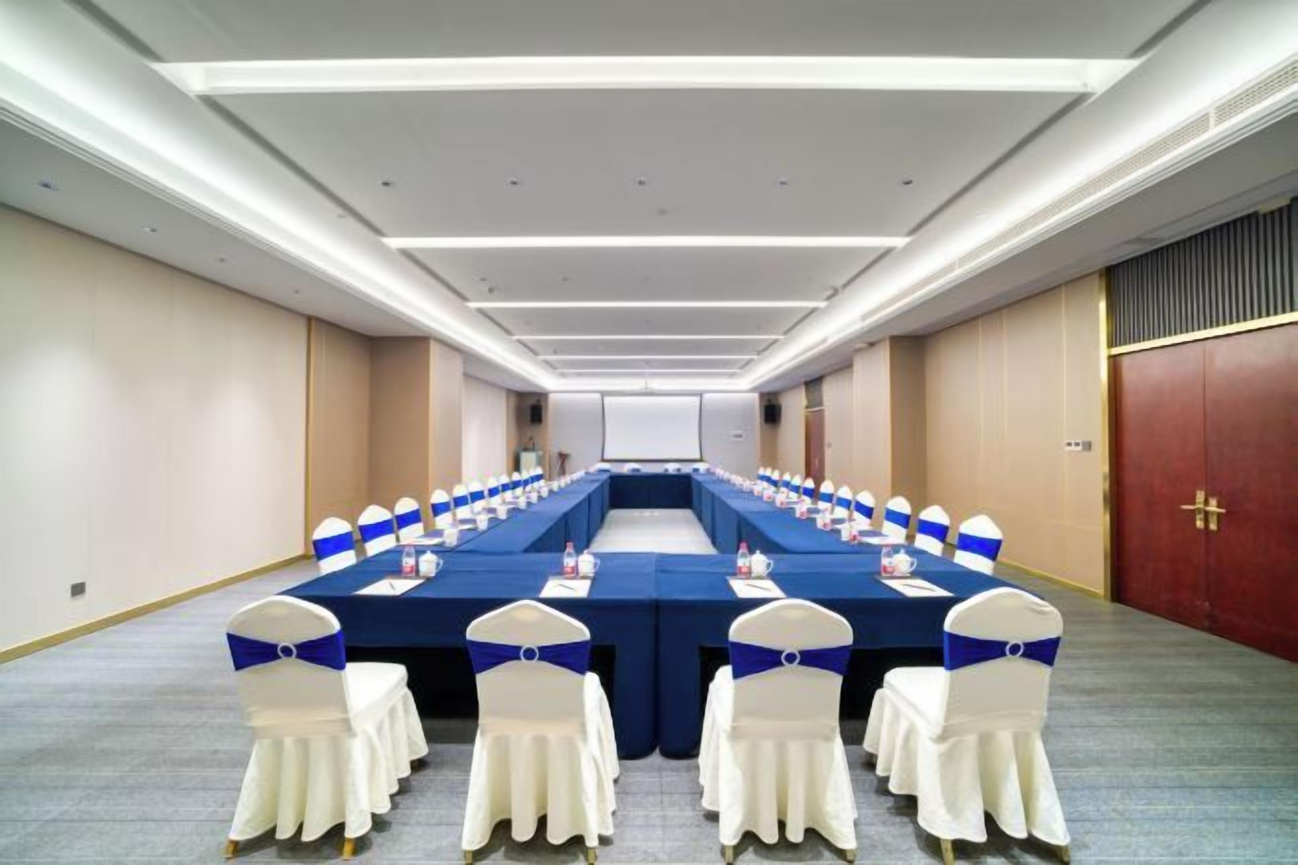 Un salón de conferencias con una larga mesa, sillas y suelo alfombrado.