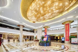 Un vestíbulo amplio con una gran estructura circular en el techo, varios niveles y una fuente decorativa central.