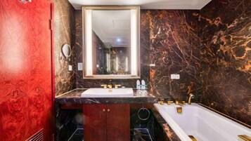 A bathroom with a marble vanity, a large mirror, a bathtub, and a red door.