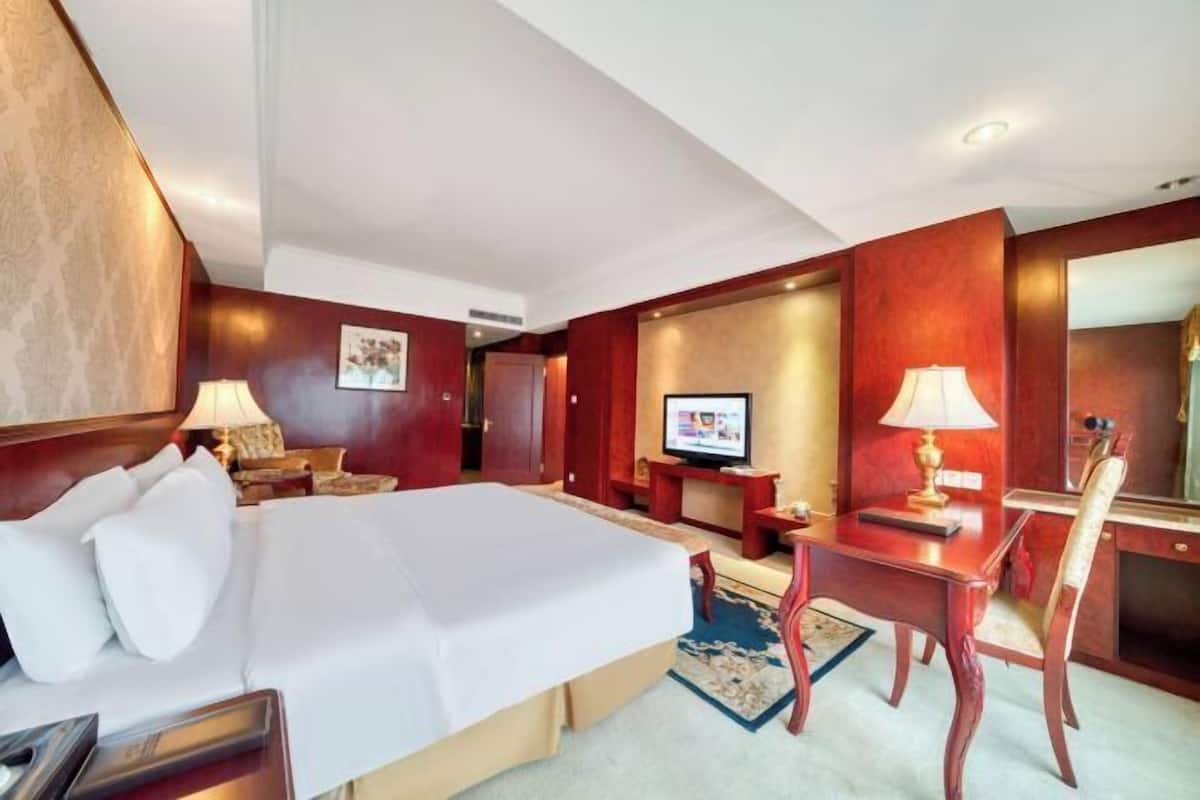 Une chambre d’hôtel avec un grand lit, un bureau, une chaise, une télévision et un miroir.