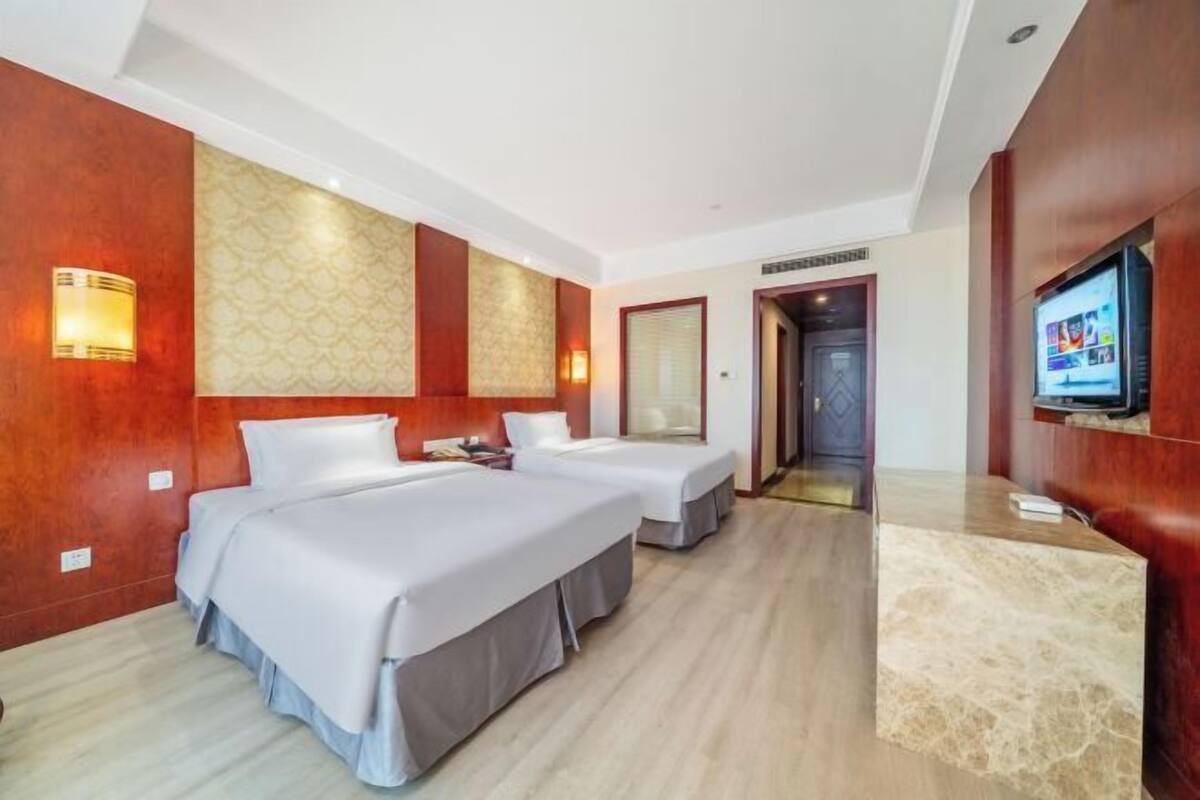 Une chambre d’hôtel avec deux lits, une télévision, un bureau et un espace de réception.