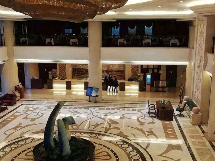 A hotel lobby with a central fountain, multiple seating areas, and a reception desk.