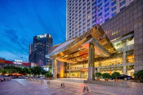 A modern hotel with a prominent entrance, large columns, and a well-lit facade.. Linhai Double-Dove Peace International Hotel