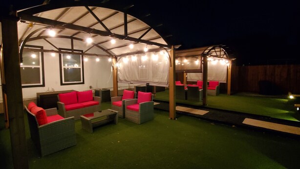 An outdoor patio with a covered seating area, artificial turf, and string lights. - Duplex - Unit B Near DWTN & Austin-Bergstrom Airport (Austin)