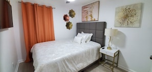 A bedroom with a bed, a nightstand, a lamp, and decorative wall art.