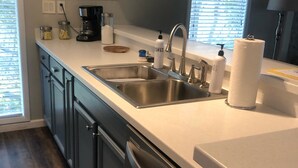 Een moderne keuken met roestvrijstalen apparatuur, een dubbele spoelbak en een raam met zonwering.