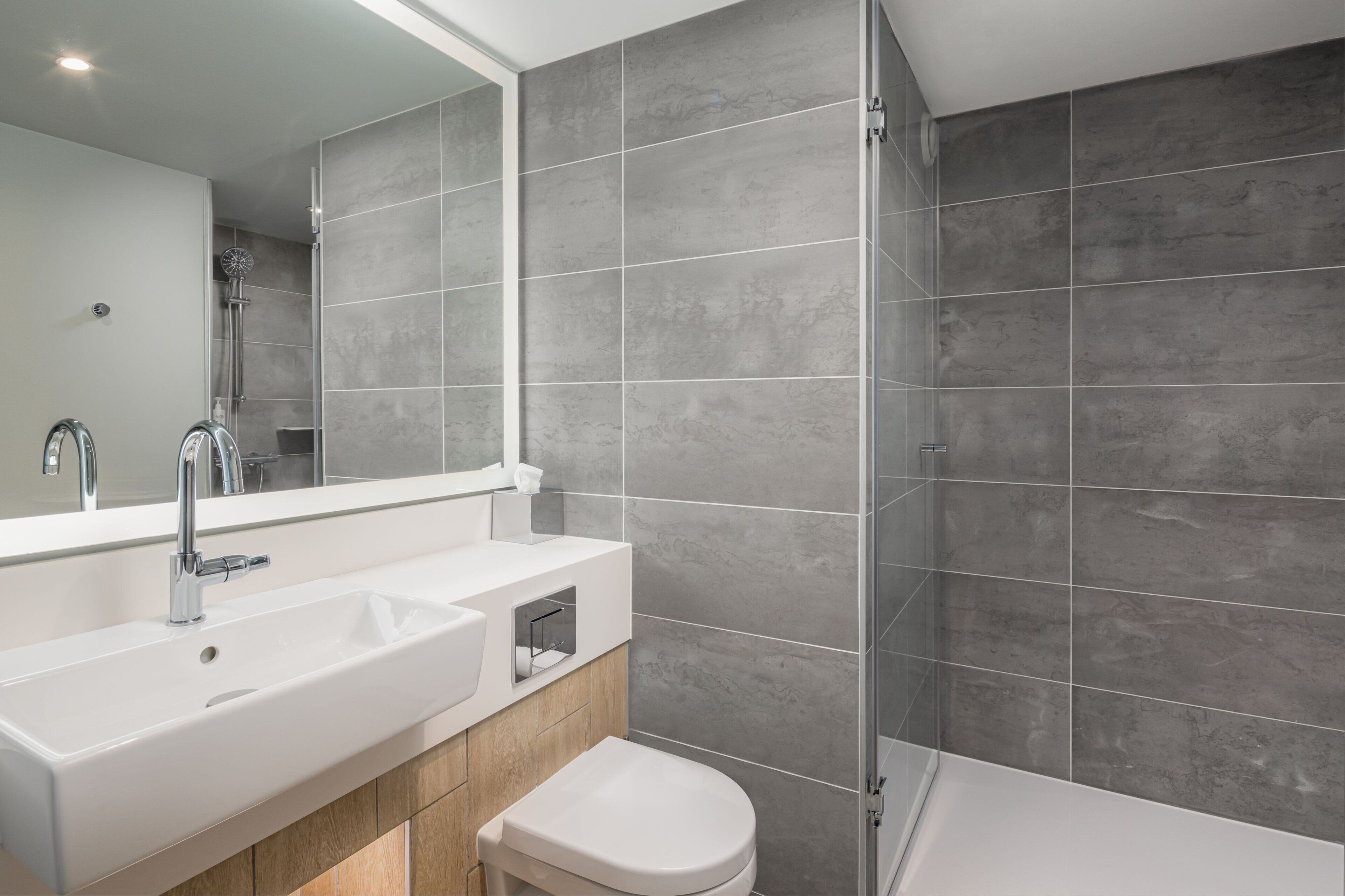 Une salle de bain moderne avec un grand lavabo, un miroir et une douche.