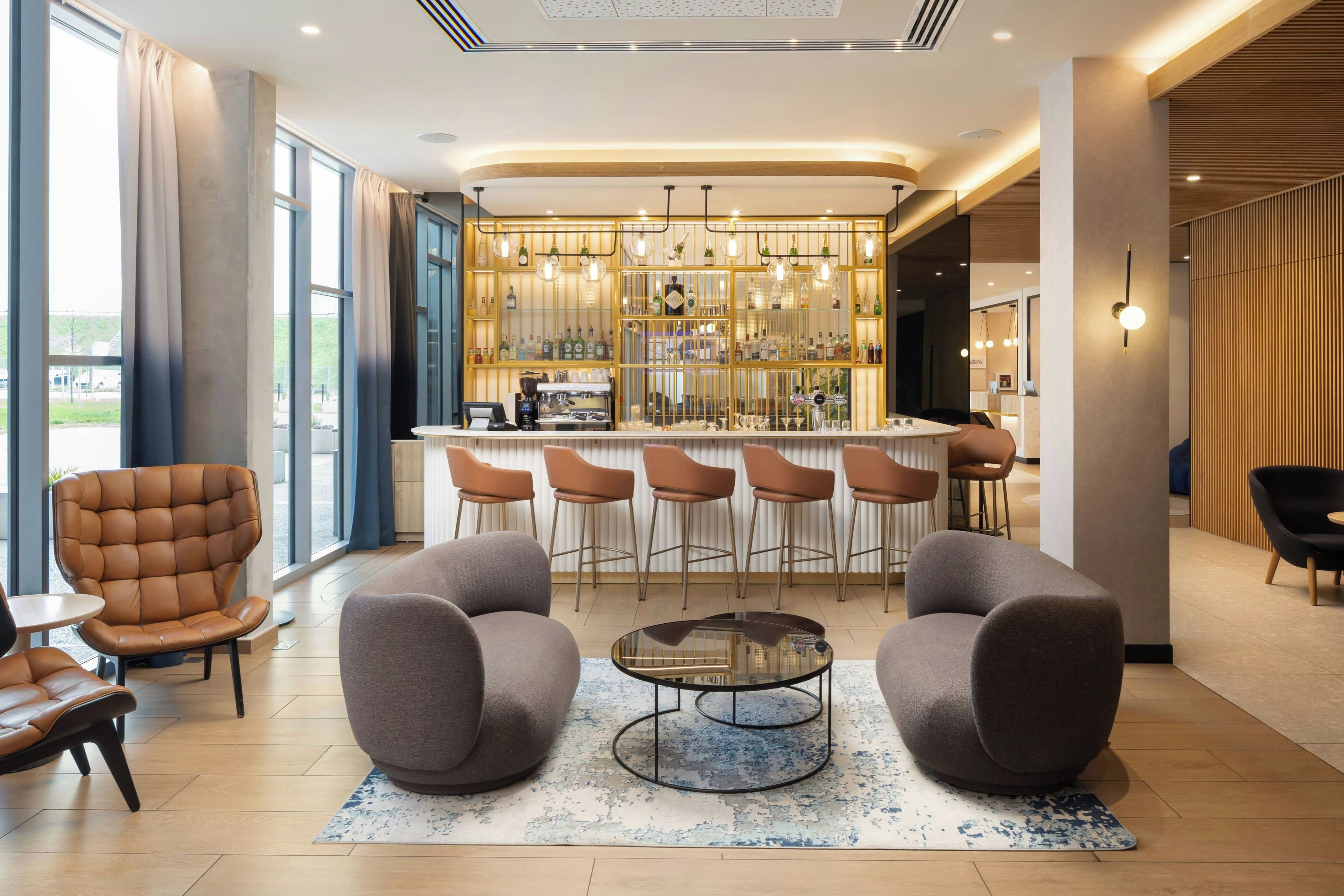 Un área de bar moderna con mostrador, taburetes y una máquina de café.