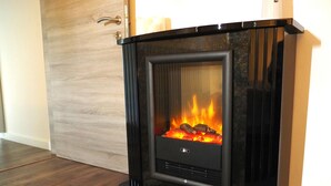 A modern fireplace with a glass front, a door with a handle, and a wooden floor. - Comfortable apartment, close to downtown and train station (Brugge)