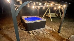 Een hottub onder een overdekte ruimte met lichtslingers.