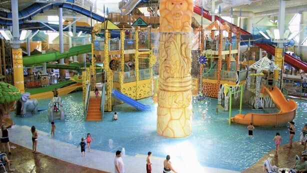 Een overdekt waterpark met meerdere glijbanen en speelconstructies.