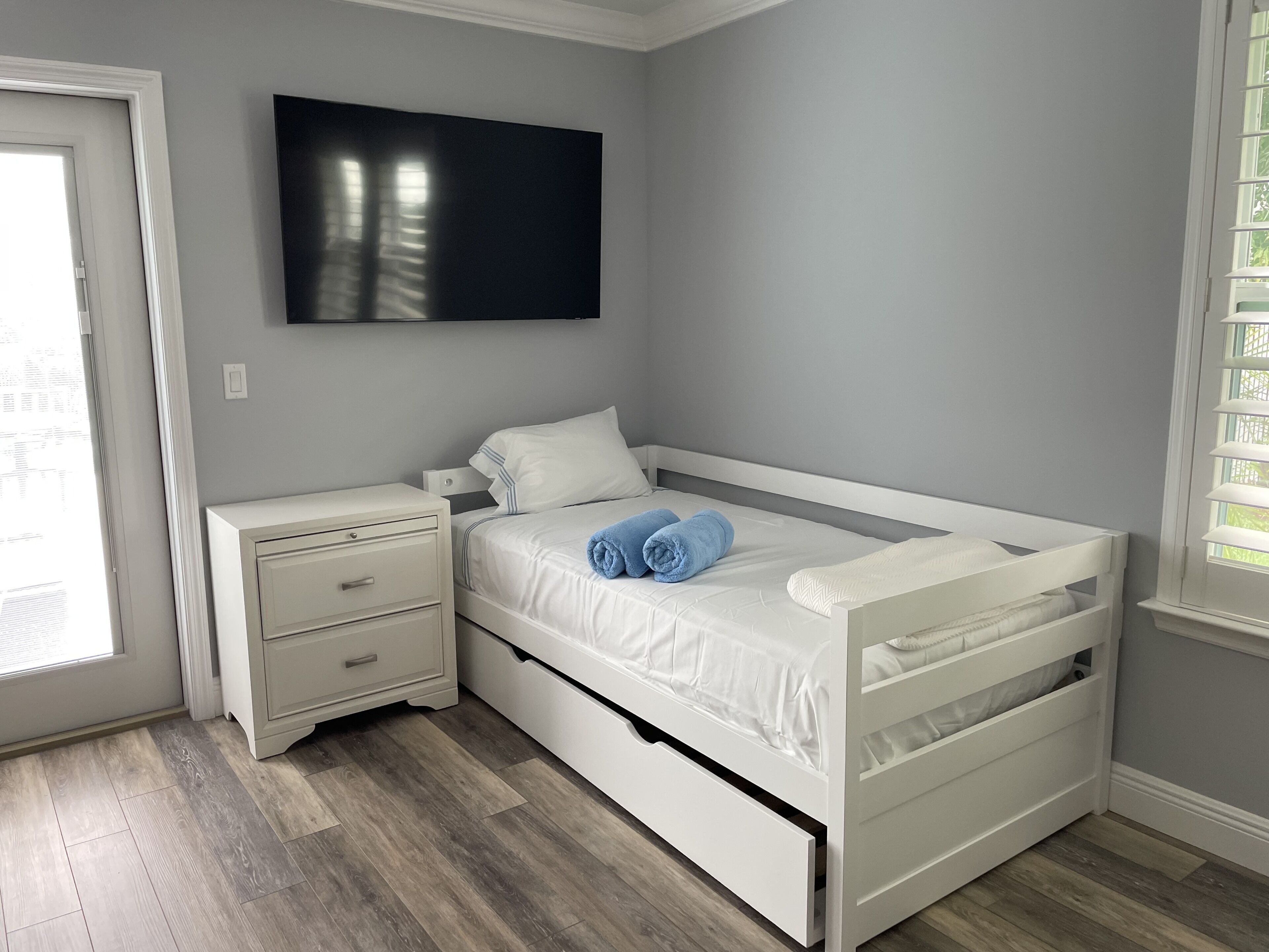 Une chambre à coucher avec un lit, une table de chevet et un téléviseur fixé au mur.