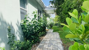 A paved pathway leading to a building with a white exterior and a brick facade.