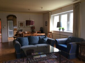 A living room with a sofa, coffee table, and a dining area with a table and chairs.