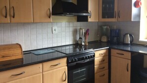 A kitchen with wooden cabinets, a black stove, and a tiled backsplash. - Spacious villa with fireplace (Vidochov)
